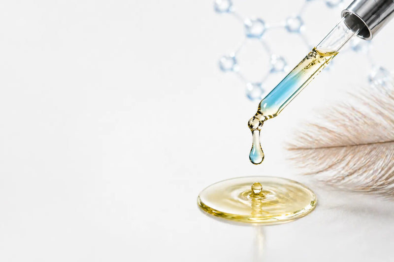 Emu oil dropper with blue copper peptide tint dripping into oil with feather and molecular background on white